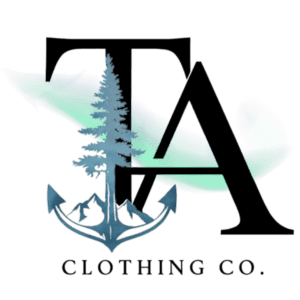 Tamarack Atlantic Clothing Co. official logo, 300x300px, transparent. A tamarack tree that is rooted in a ship anchor. Mountain peak elements can be seen behind the anchor. Large, majestic letters "TA" tower over the tamarack tree as northern lights whisp across the logo.